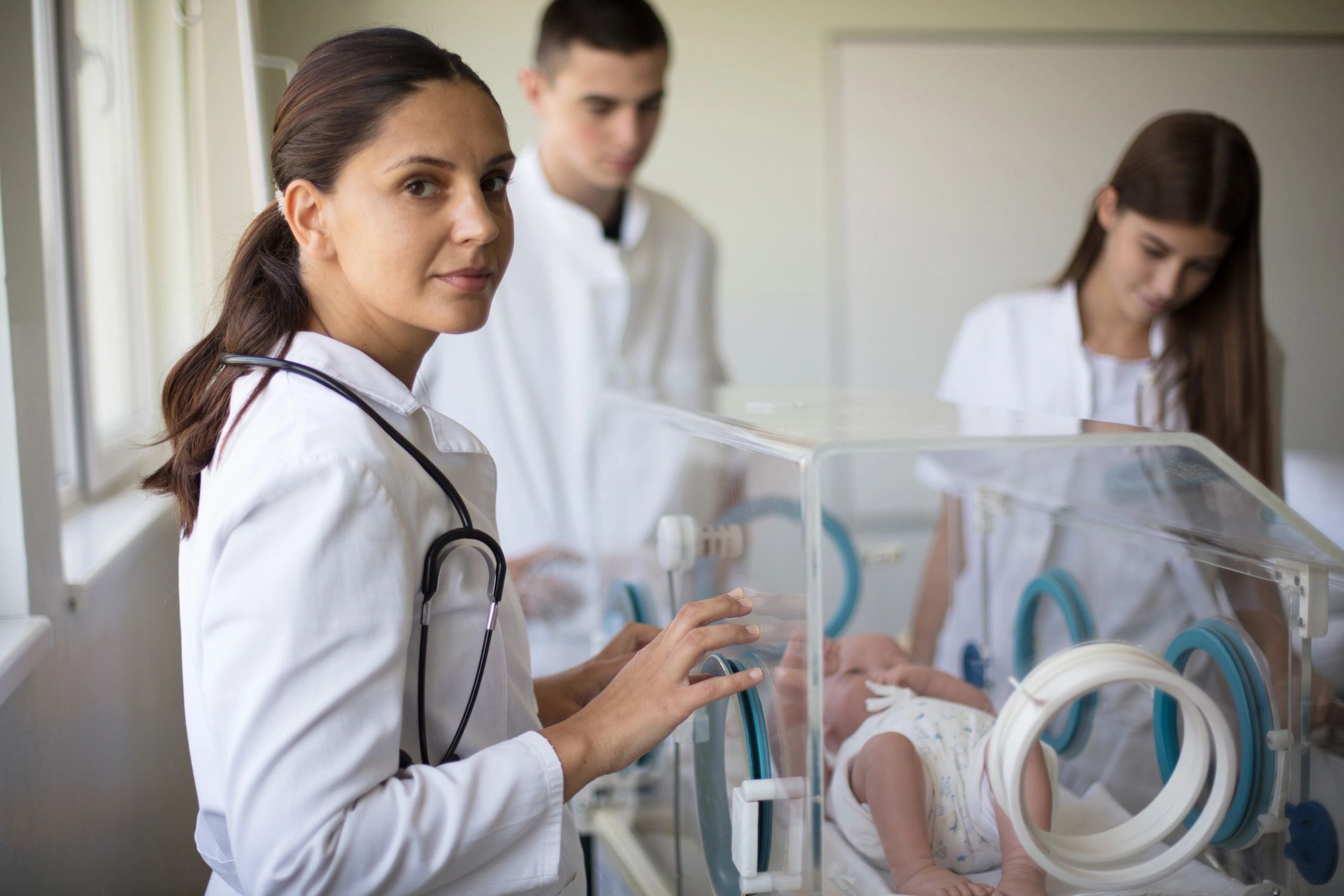 Doctor taking care of newborn baby in incubator.
